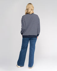 Person wearing a striped sweater and blue jeans on a white background