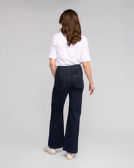 Person wearing dark blue jeans and a white shirt on a gray background