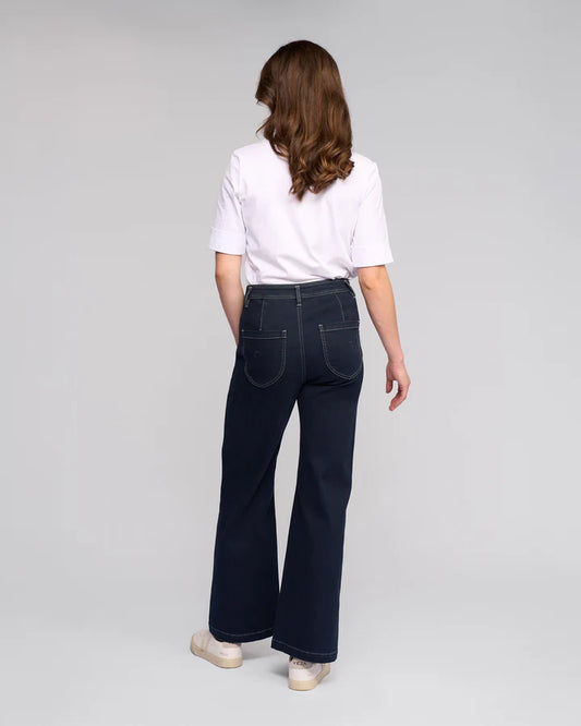 Person wearing dark blue jeans and a white shirt on a gray background