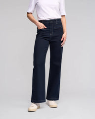Person wearing dark blue jeans and a white shirt on a gray background