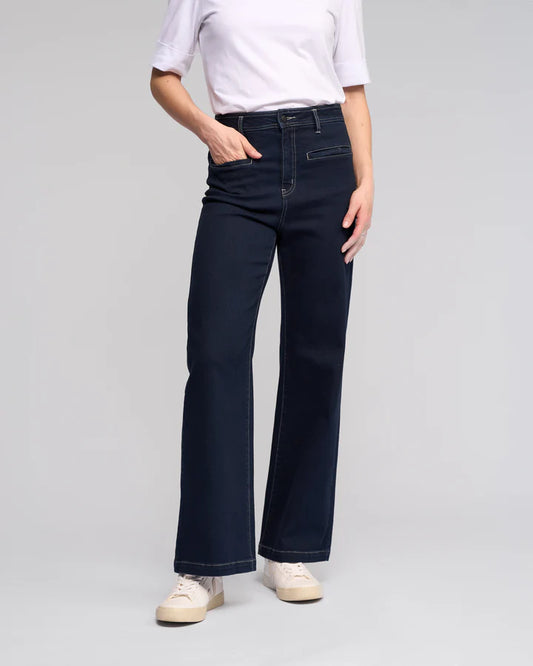 Person wearing dark blue jeans and a white shirt on a gray background