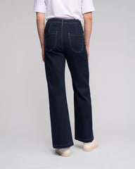 Person wearing dark blue jeans on a plain background