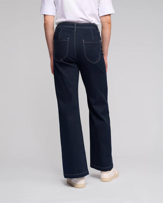Person wearing dark blue jeans on a plain background
