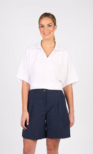 Woman wearing a white blouse and Vassalli Pleat detail navy shorts on a white background