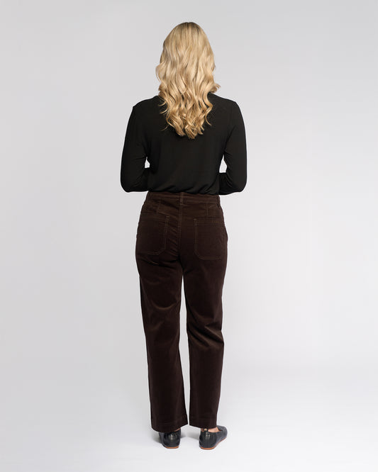Person wearing a black top and brown pants on a white background