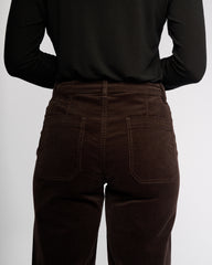 Person wearing brown corduroy pants and a black long-sleeve shirt on a white background