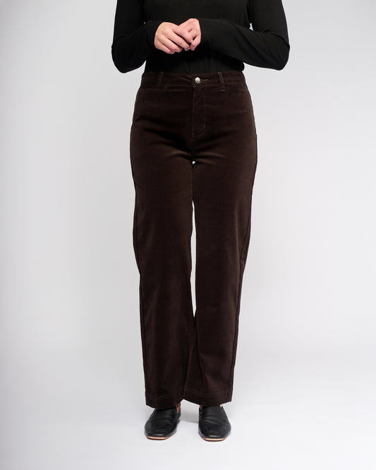 Person wearing brown pants and a black top on a white background