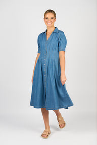 Woman wearing the Vassalli Shaped blue denim dress on a white background