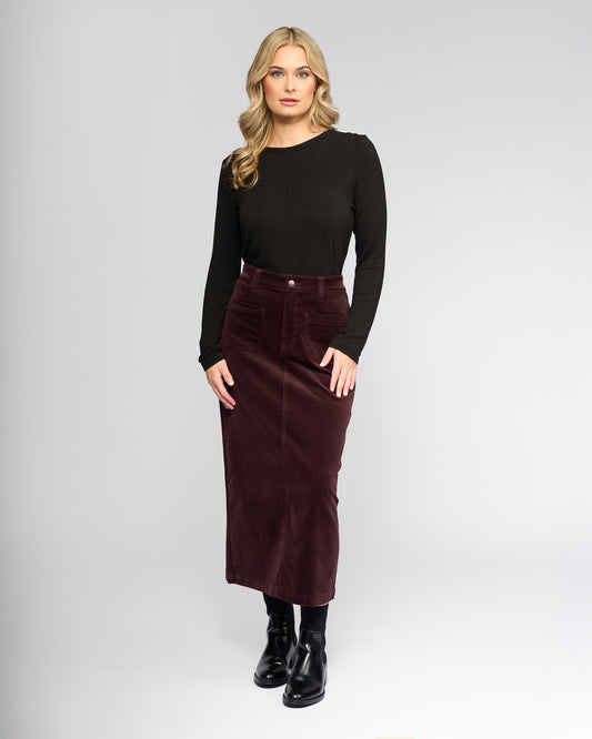 Woman wearing a black long-sleeve top and burgundy skirt on a white background