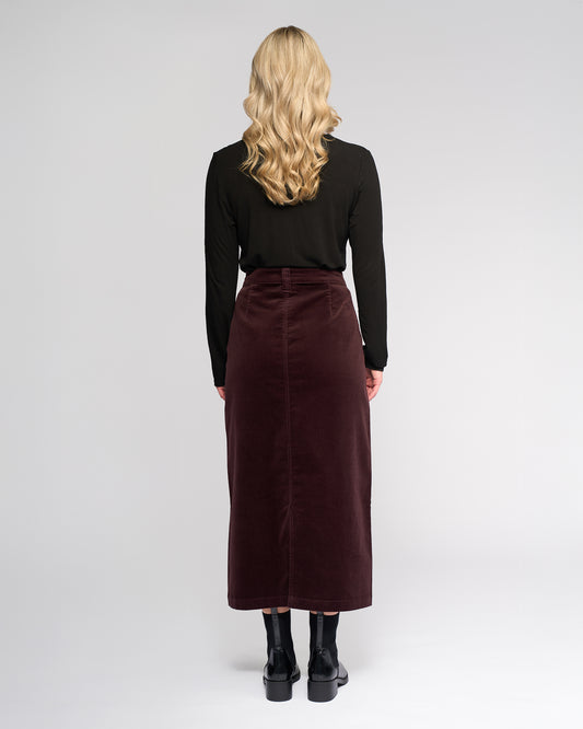 Person wearing a black top and burgundy skirt on a white background