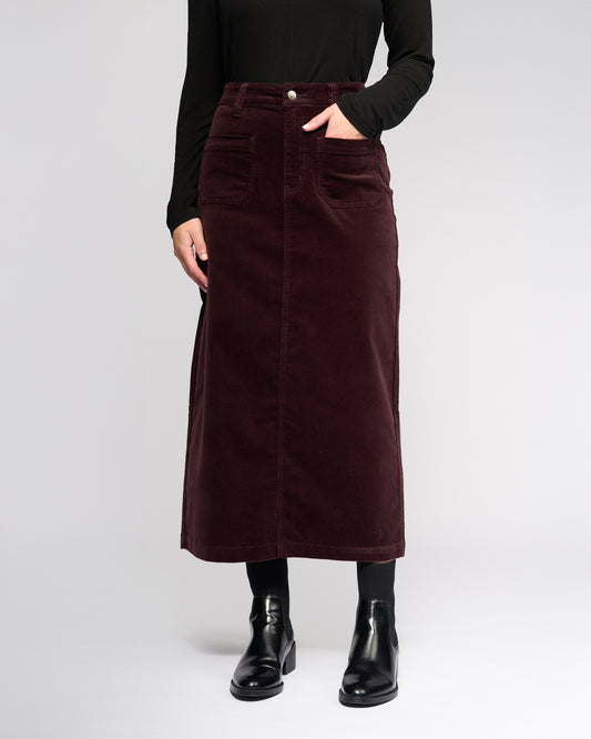 Person wearing a burgundy corduroy skirt on a white background
