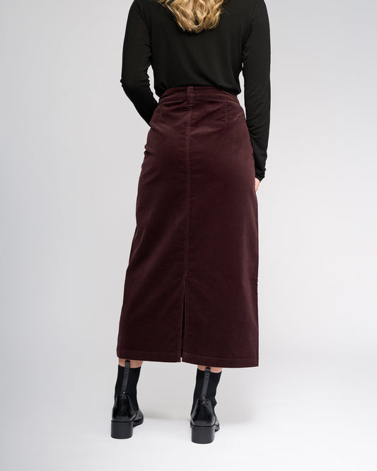 Person wearing a burgundy skirt and black top on a white background