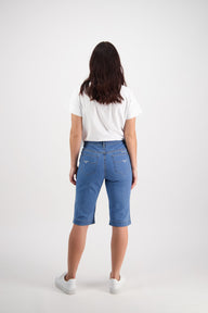Lady wearing Vassalli blue denim shorts and a white shirt on a white background