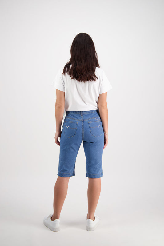 Lady wearing Vassalli blue denim shorts and a white shirt on a white background