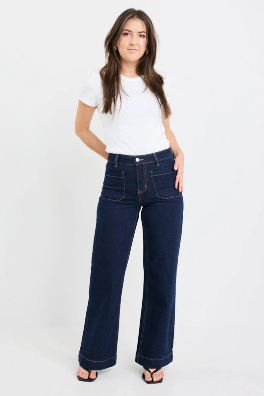 Woman wearing a white t-shirt and blue jeans on a plain background